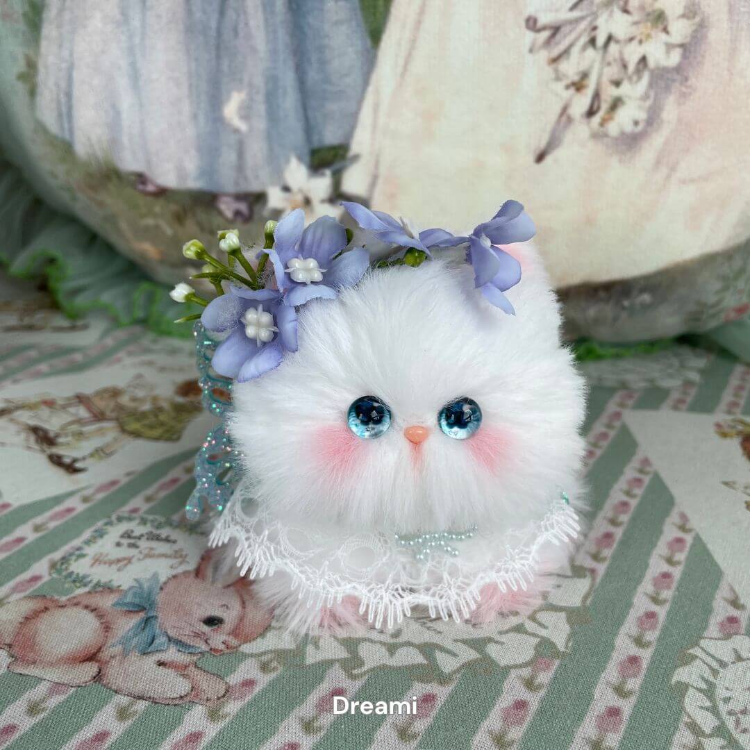 Handmade Fairy Paws plush kitten with blue eyes, floral crown, and lace collar on whimsical patterned fabric.