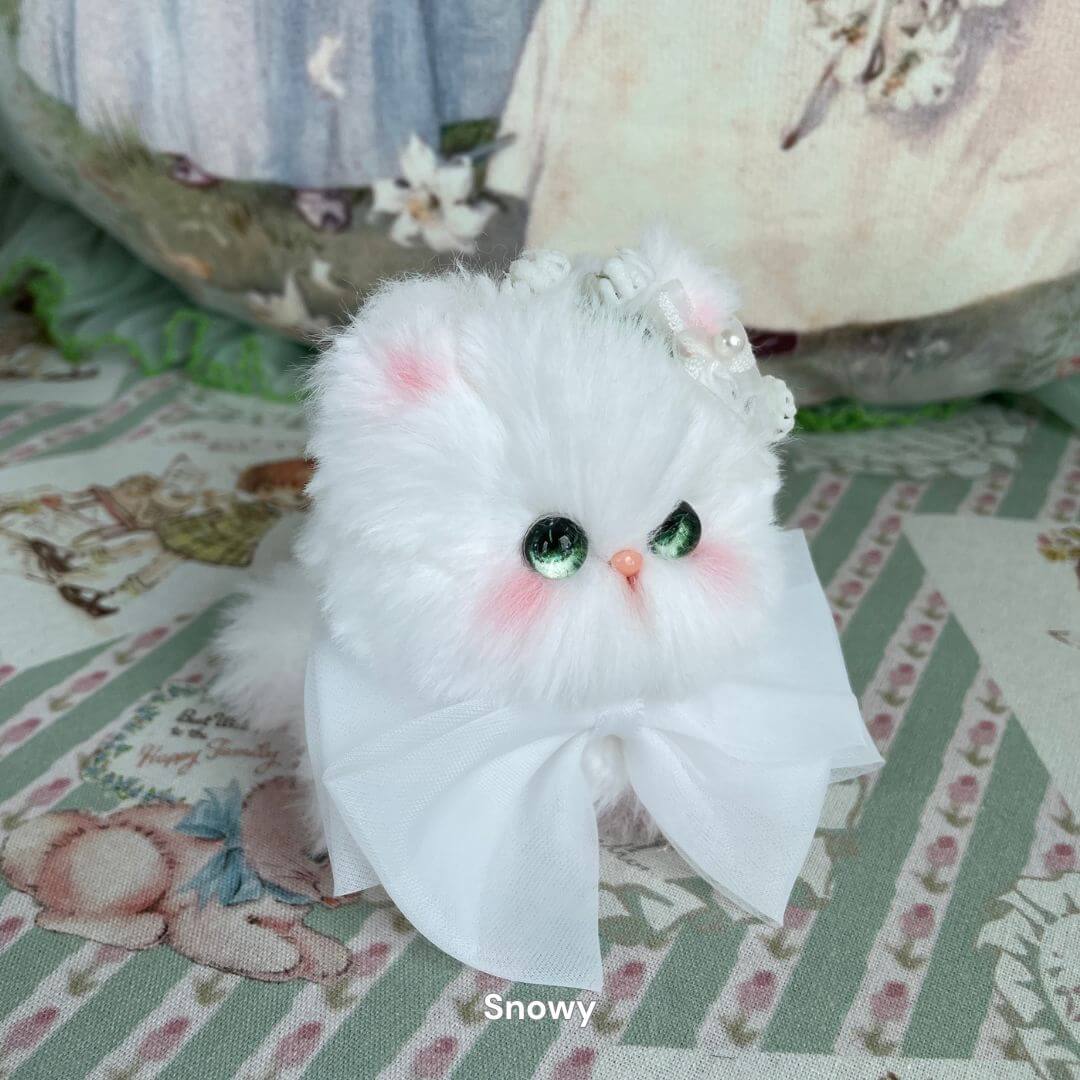 Handmade plush kitten with green eyes, wearing a pearl crown and white bow; part of the Fairy Paws Collection.
