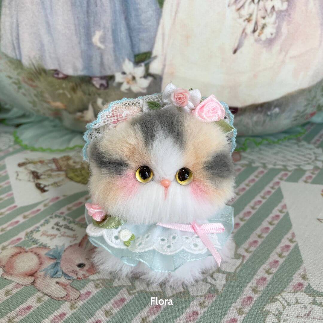 Cute calico handmade kitten from the Blossom Kitten Collection, wearing a lace bonnet and floral accents, fluffy and charming.