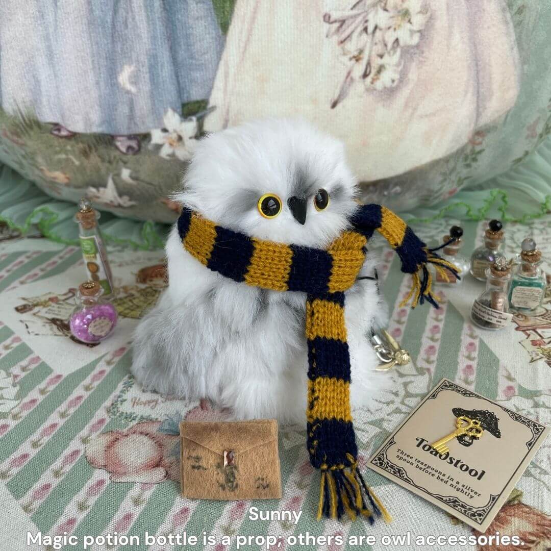 Fluffy Magic Owls: adorable snowy owl figurine with golden eyes, wearing a hand-knitted scarf, surrounded by magical accessories.