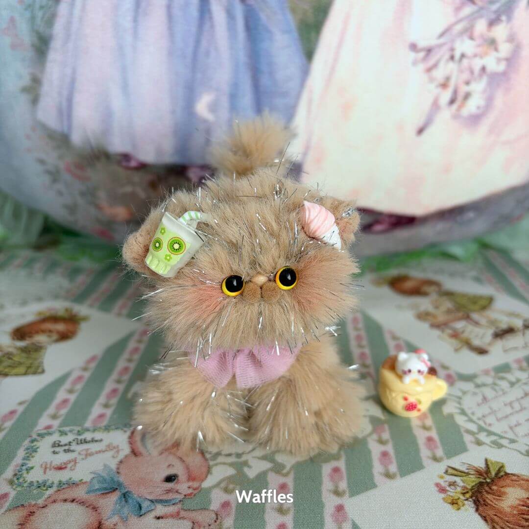 Cute beige fluffy kitten figurine with a green drink and pink bow, from the Twinkling Kitten Collection, handmade in the UK.