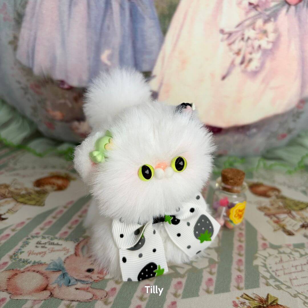 Fluffy Kitten Collection featuring a miniature white fluffy cat figurine with a black and white bow, cute eyes, and playful accessories.
