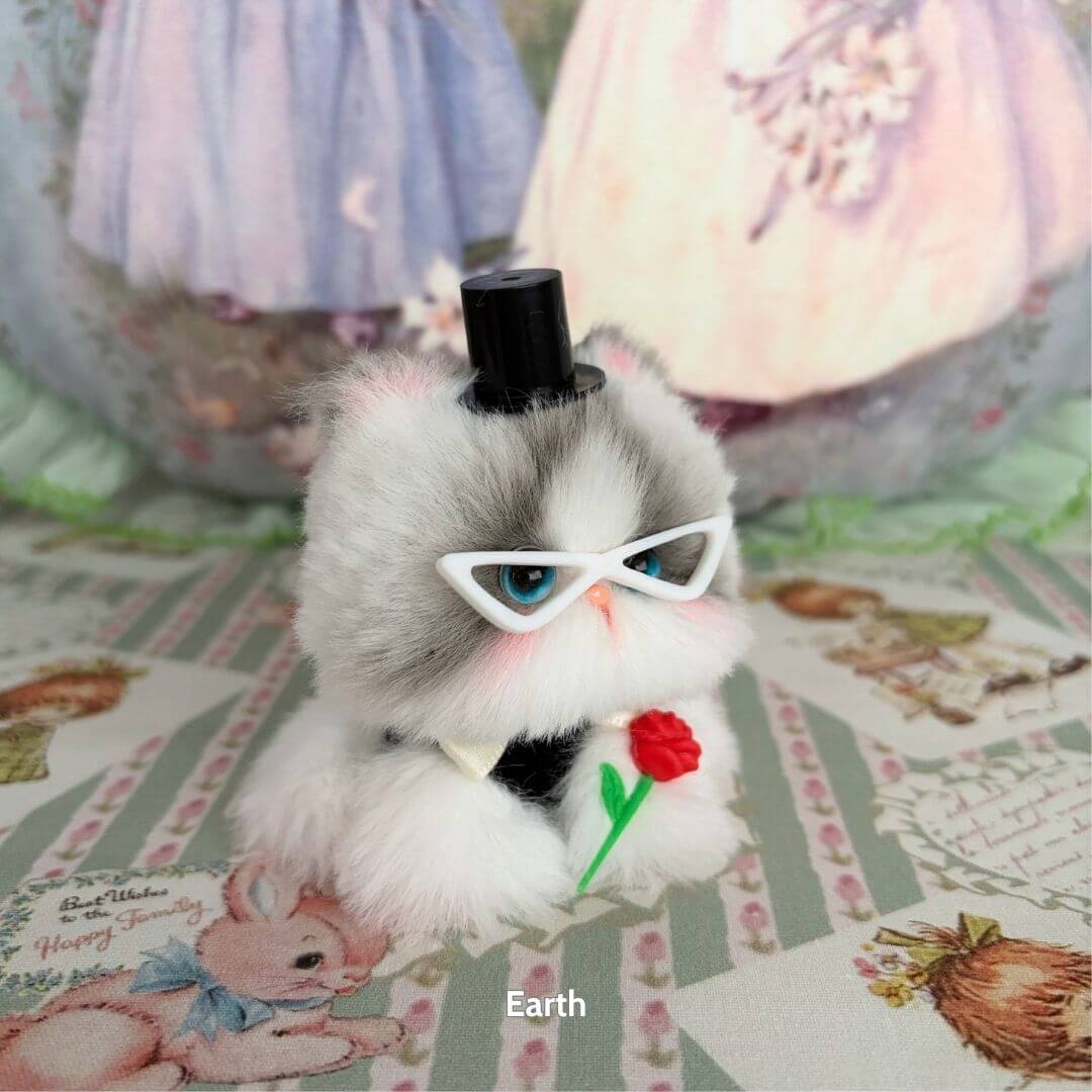 Moonbound Companions handmade kitten wearing a top hat and glasses, featuring fluffy white and gray fur, holding a rose.