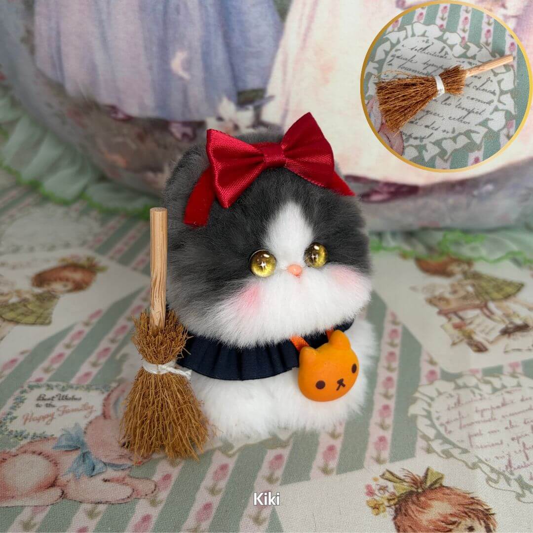 Handmade kitten from the Cosplay Kitten Collection, a fluffy black and white cat figurine with a red bow and broom, perfect for magical adventures.
