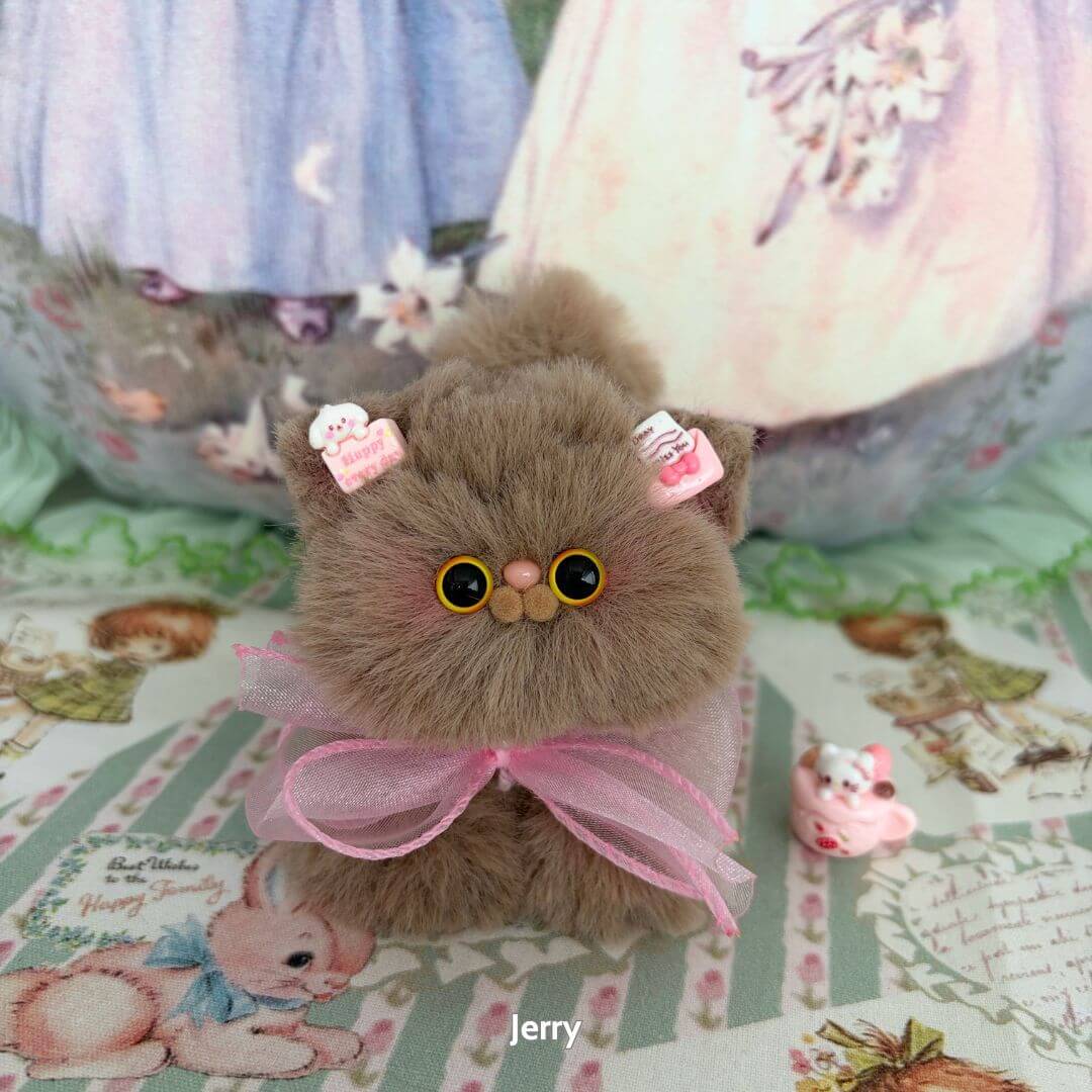 Fluffy Kitten Collection: cute brown fluffy kitten figurine with bows and sweets, handmade kawaii cat decor on patterned background.
