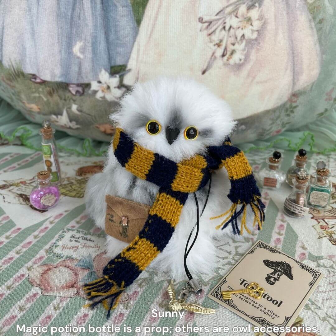 Fluffy Magic Owls: Handmade snowy owl figurine with golden eyes, wearing a knitted striped scarf, surrounded by magical accessories.