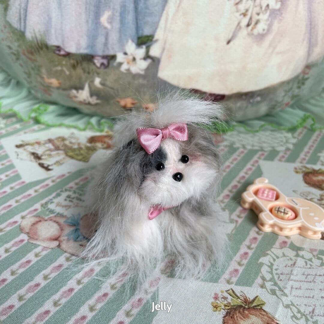 Fluffy Puppy Collection handmade miniature dog figurine with grey fur and pink ribbon, sitting on a pastel patterned table.