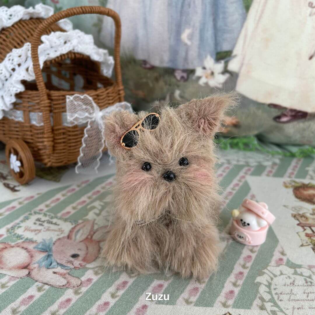 Handmade plush puppy toy with sunglasses and a pink accessory, styled in a vintage setting. Part of the Fluffy Puppy Collection.