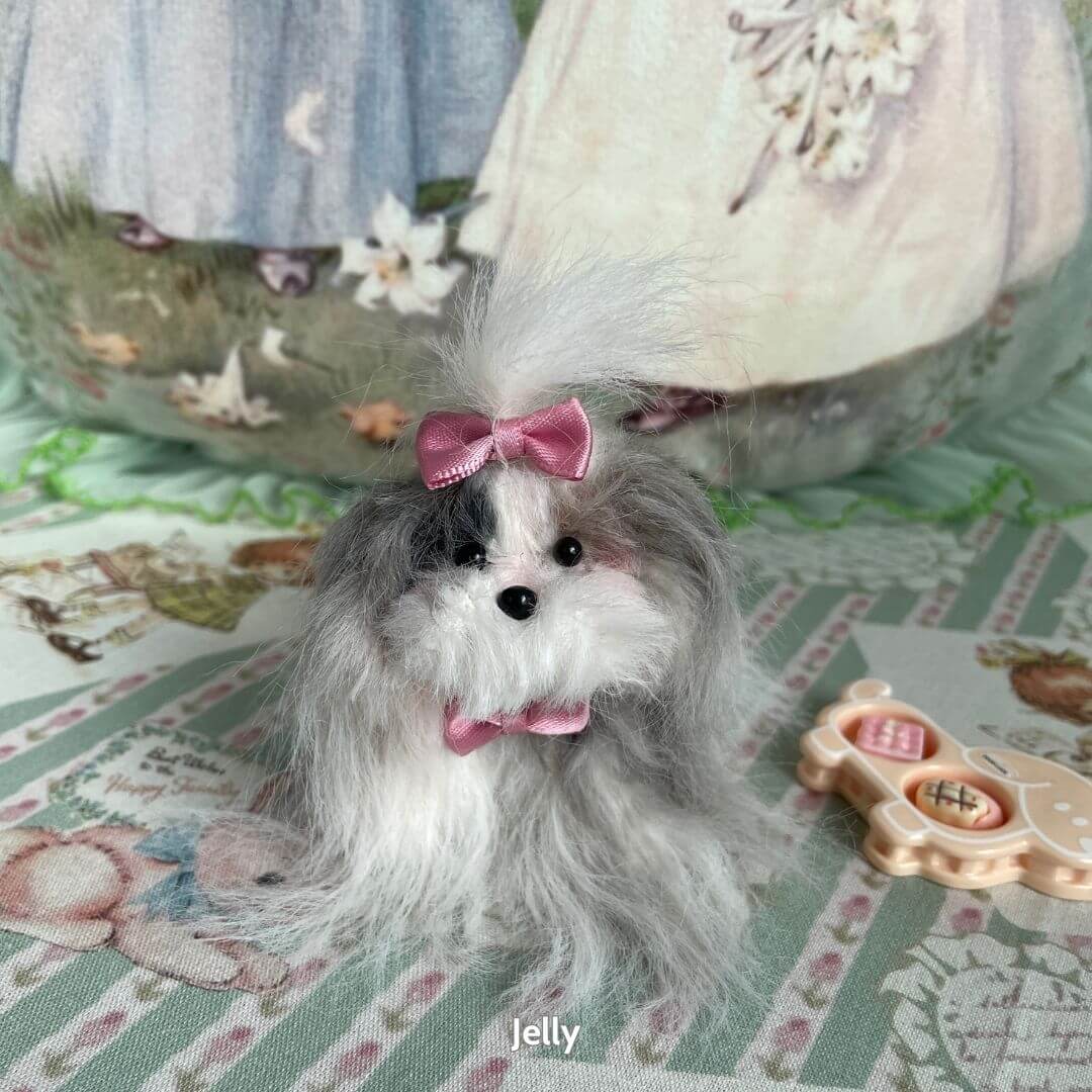 Alt Tag: Fluffy Puppy Collection handmade long-haired miniature dog figurine with pink bow, soft gray fur, sitting on patterned background.