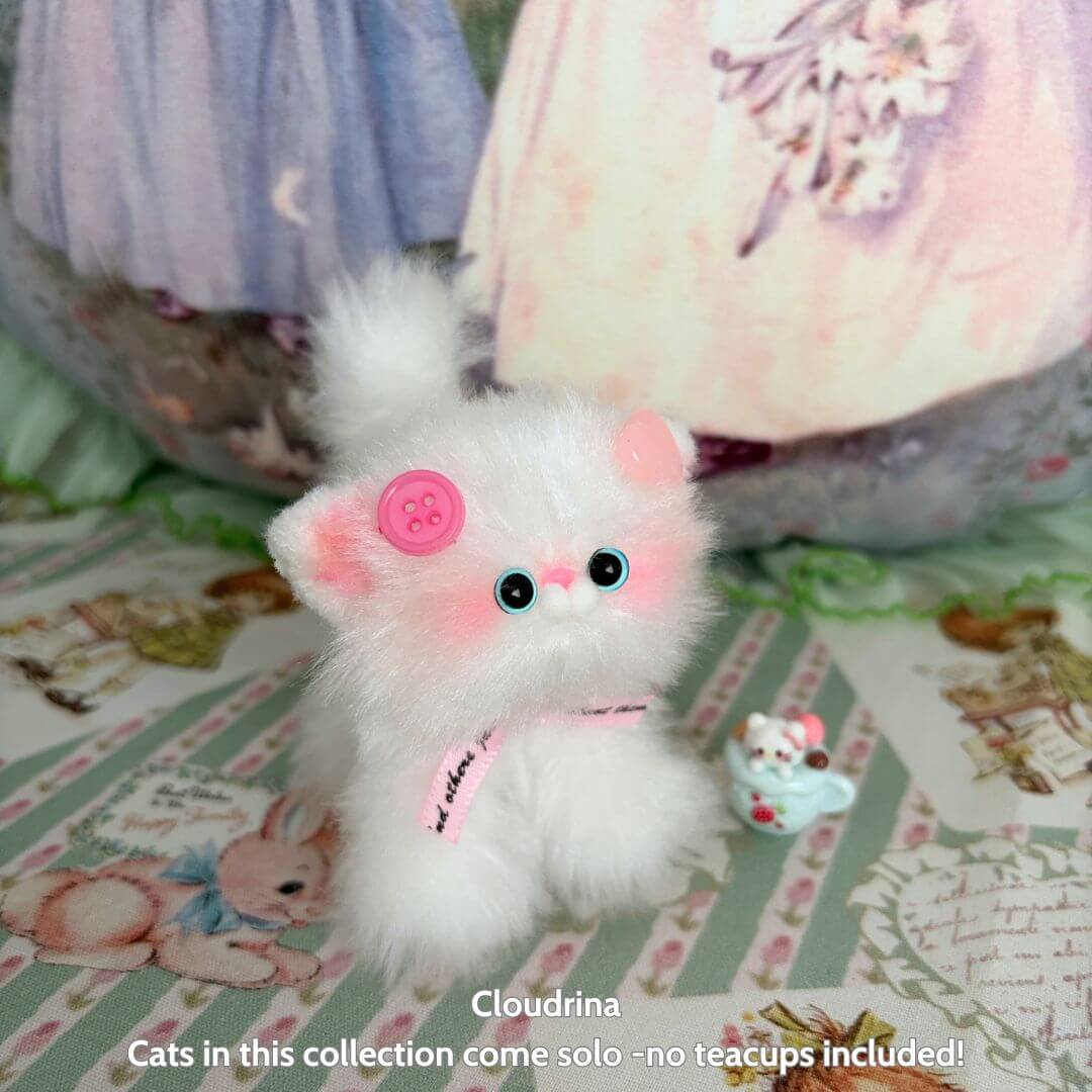 Fluffy white cat toy with pink ears and buttons. Cat has reflective skin and a collar with a tag. Background is a colorful floral pattern.