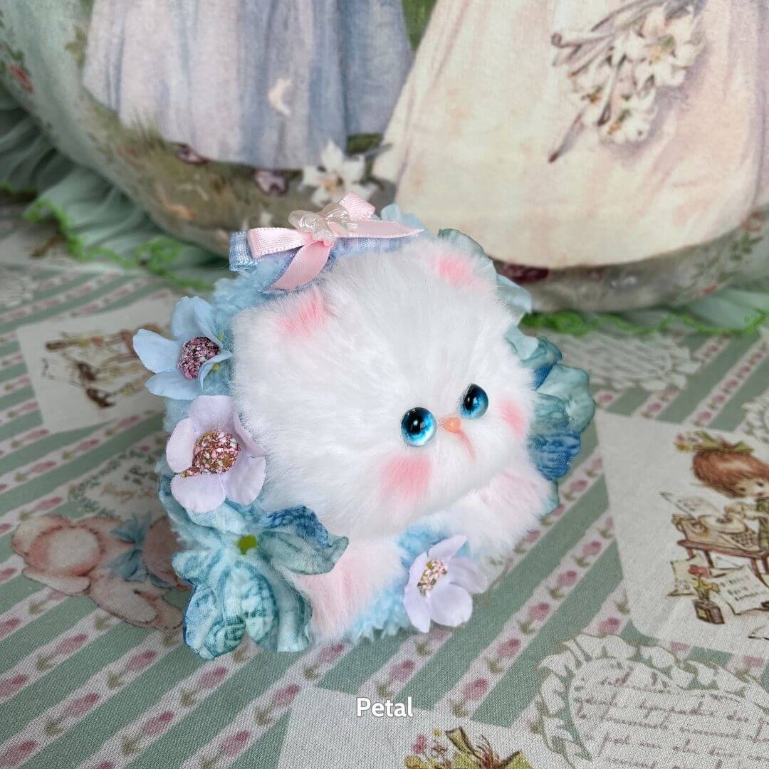 Adorable handmade kitten from the Blossom Kitten Collection, featuring fluffy white fur, blue floral accents, and a pink bow.