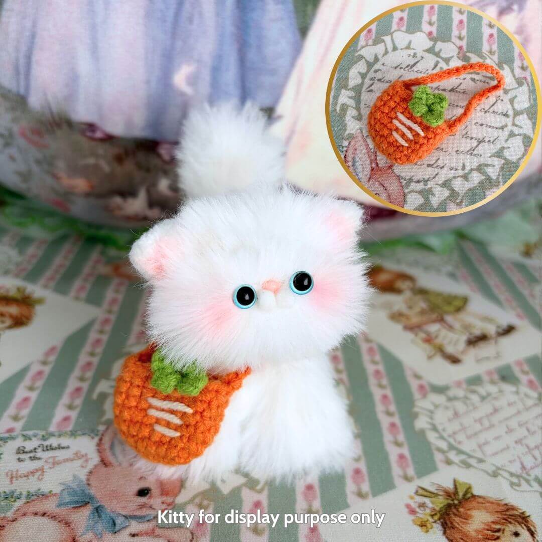 Handmade kitten with fluffy white fur, wearing a cute orange carrot sling, from the Snuggle Bits collection.