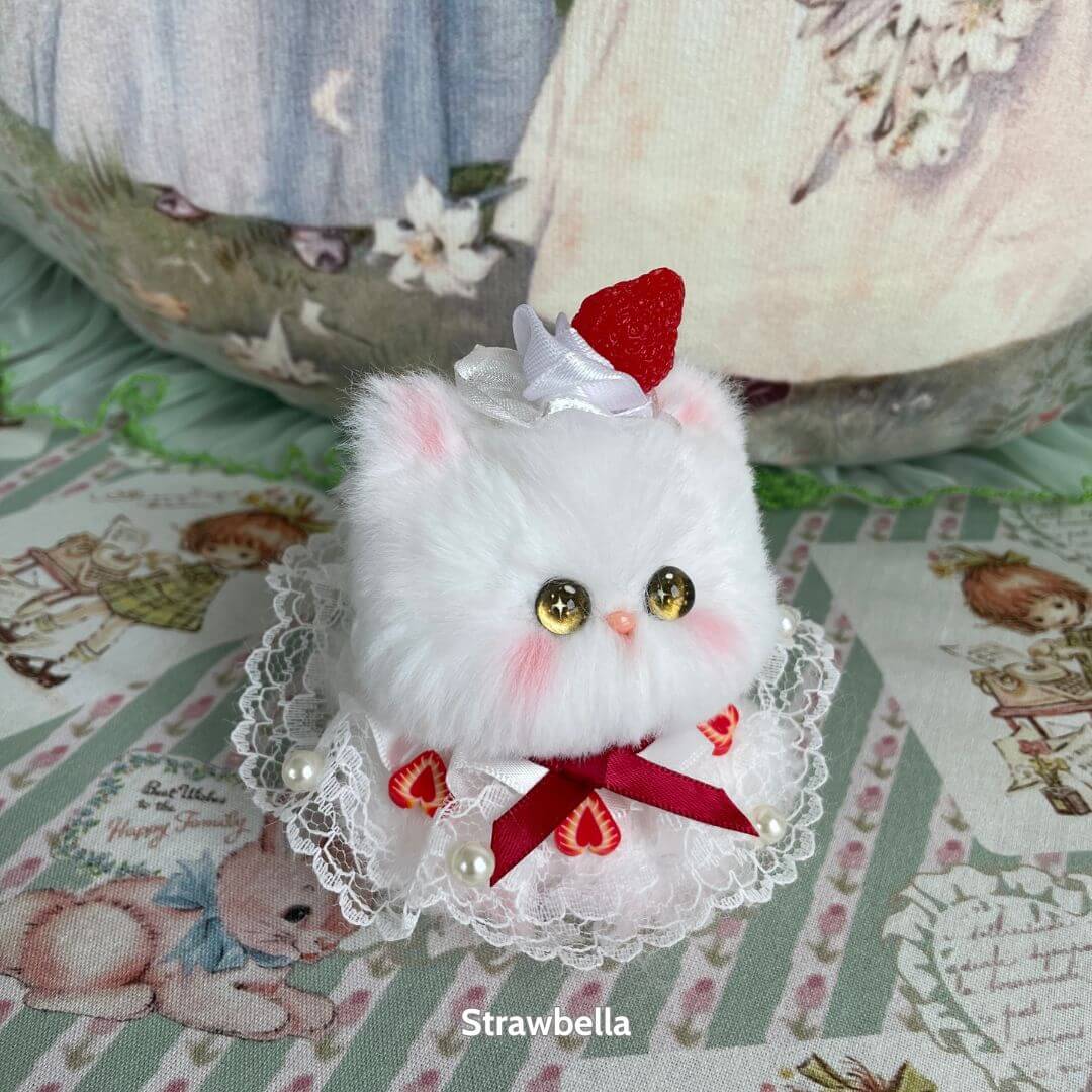 Handmade kitten from Mewlicious Collection, fluffy white cat figurine with strawberry hat, dressed in lace and ribbon, cute collectible.