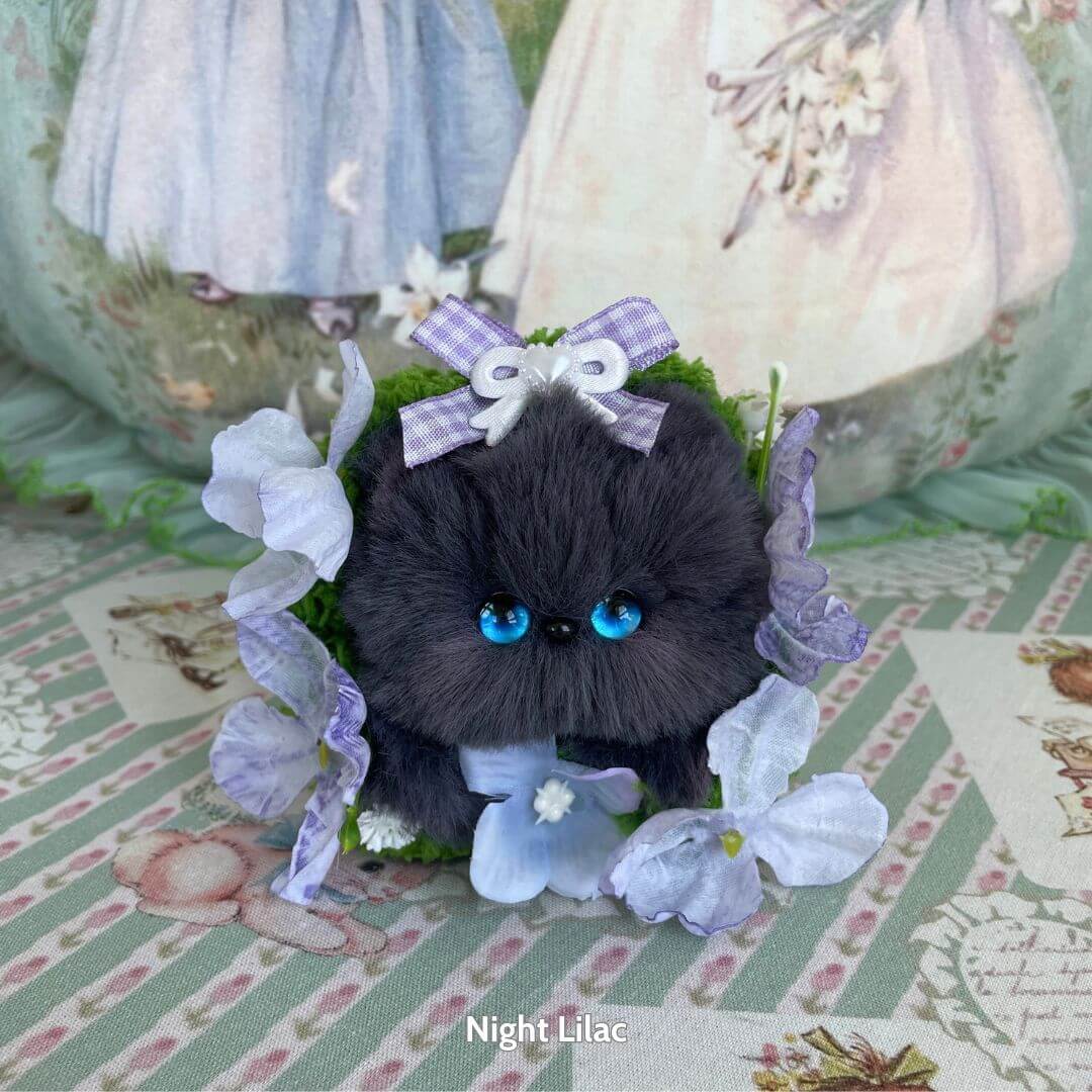 Handmade kitten from the Blossom Kitten Collection, fluffy black mini cat figurine with blue eyes, adorned with lilac flowers and a bow.