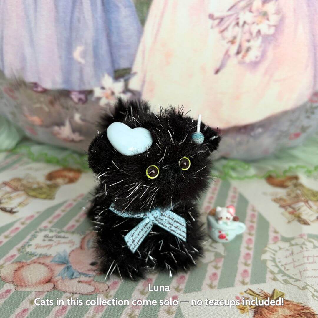 Twinkling Kitten Collection: handmade black kitten figurine with fluffy fur, heart-shaped bow, and shimmering accents.