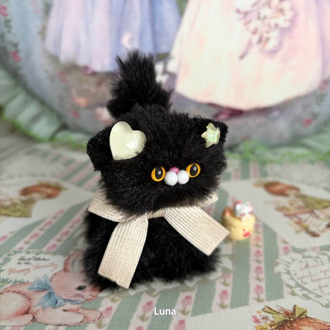 Cute black handmade kitten from the Glossy Meowgic Collection, adorned with stars, bow, and fluffy details.