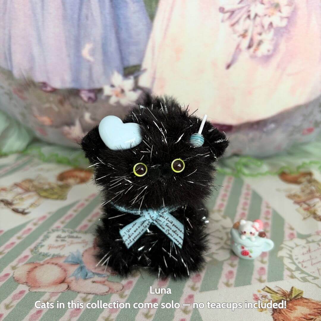 Handmade Twinkling Kitten Collection black fluffy cat figurine with blue bow and cute heart accessories.