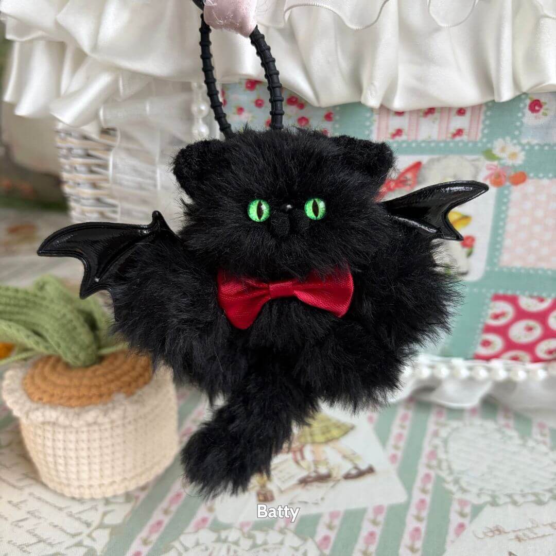 Winged Kitty Pendants featuring a fluffy black kitten with bat wings and bright green eyes, wearing a red bow tie.