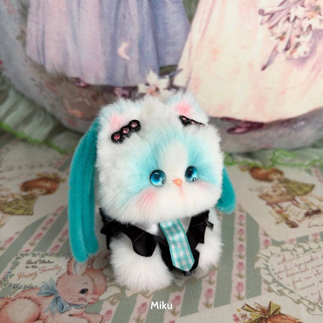 Adorable handmade kitten from the Cosplay Kitten Collection, featuring blue and white fluffy fur, cute black outfit, and accessories.