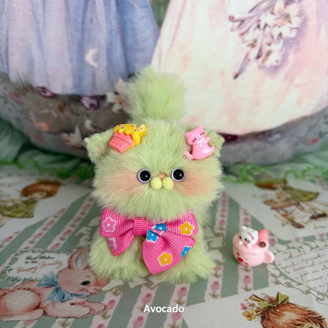 Adorable fluffy kitten figurine in mint green, wearing a pink bow and festive fruit-themed accessories from the Fruity Kitten Collection.