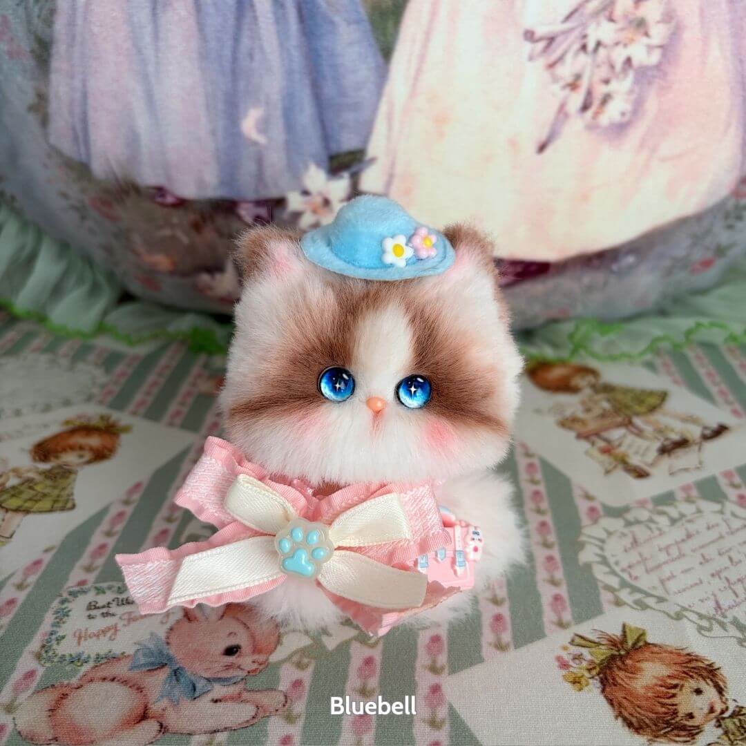 Handmade kitten from the Cosplay Kitten Collection, a fluffy cat figurine with blue eyes, wearing a blue hat and pink bow.