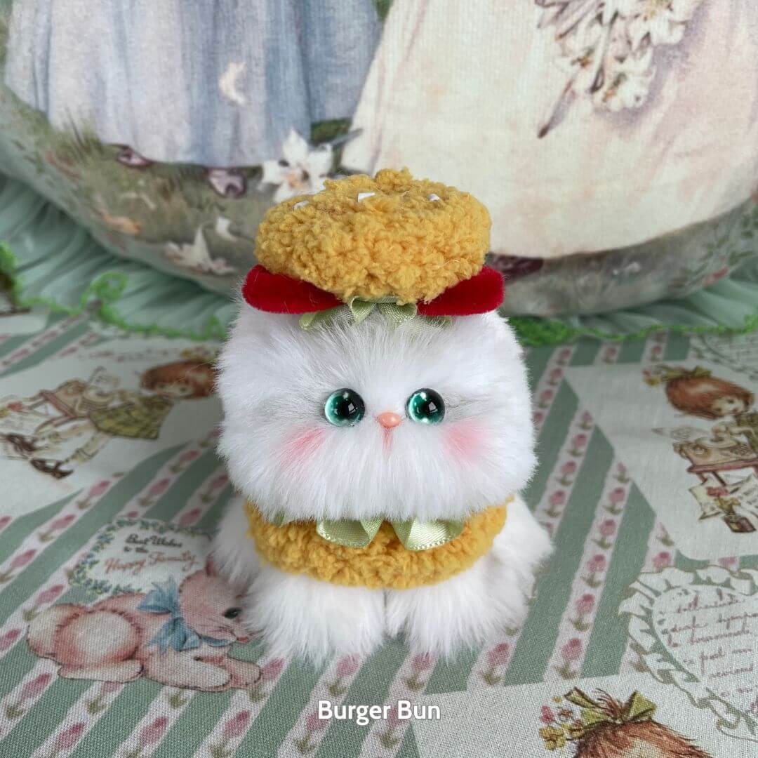 Mewlicious Collection: cute handmade kitten figurine with fluffy white fur, dressed as a burger bun, featuring green eyes and a red bow.