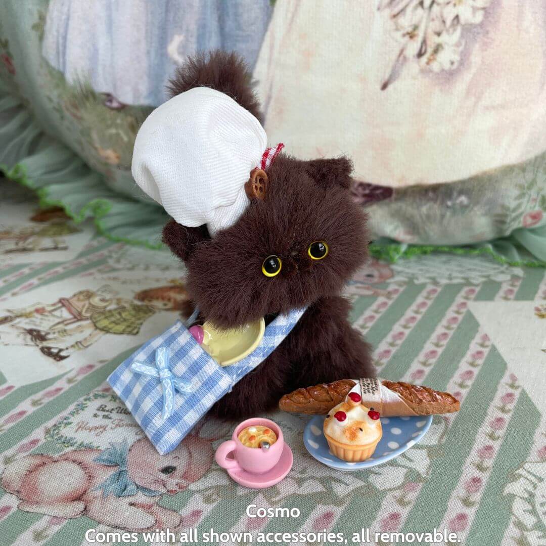 Cute handmade kitten in a chef's hat and apron, surrounded by miniature treats and cooking accessories, Purrfect Chef Kitten Sets.