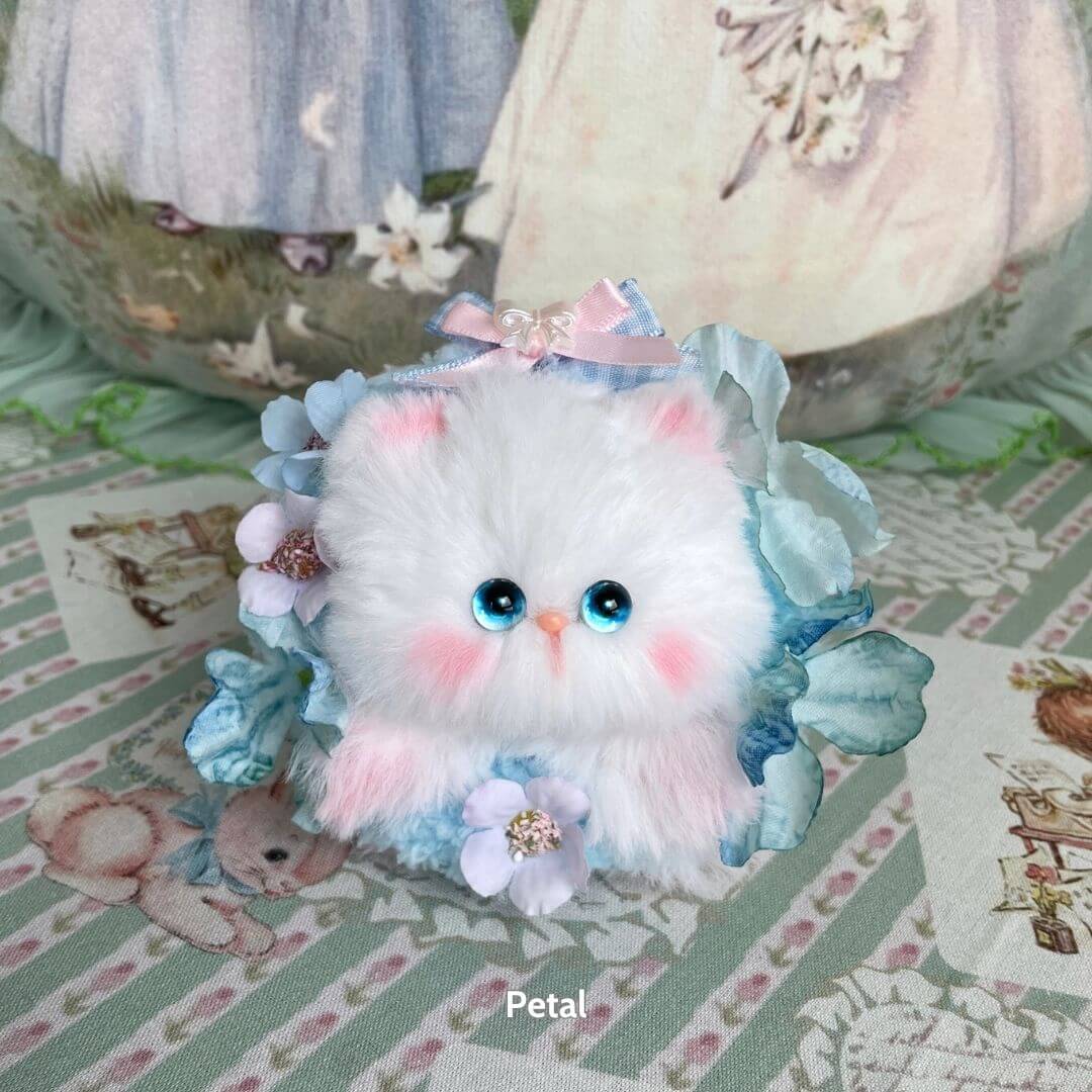 Adorable white fluffy kitten from the Blossom Kitten Collection, adorned with blue flowers and a pink bow, cute and collectible.