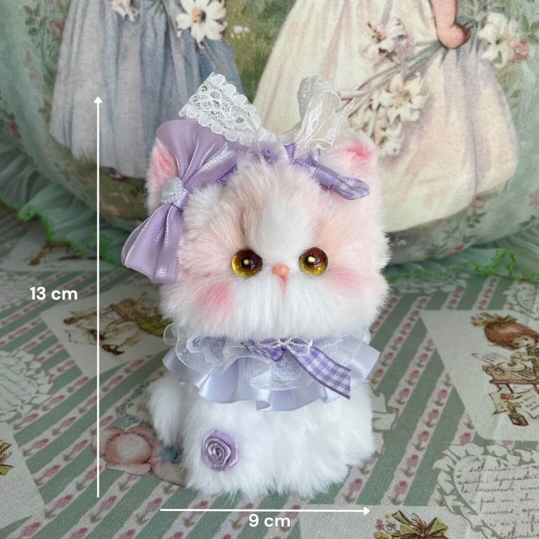 Cute fluffy kitten figurine from the Enchanted Big Paws Collection, wearing a purple bow and ruffled collar, perfect for home decor.