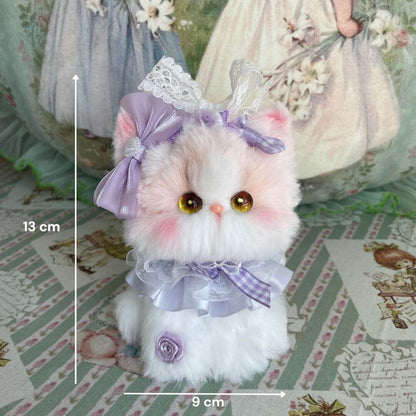 Cute fluffy kitten figurine from the Enchanted Big Paws Collection, wearing a purple bow and ruffled collar, perfect for home decor.