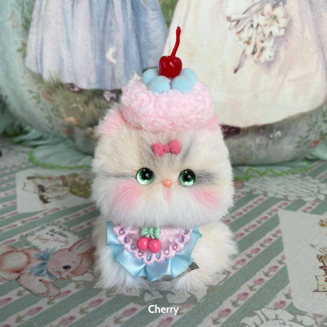 Handmade kitten from the Mewlicious Collection, fluffy white and pastel colors, dressed like a cherry cupcake, cute collectible decor.