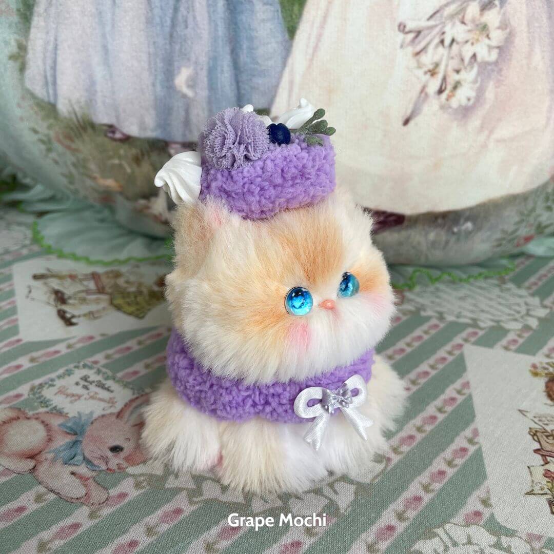 Mewlicious Collection: Adorable fluffy kitten figurine with blue eyes, wearing a purple outfit and flower hat, cute collectible.