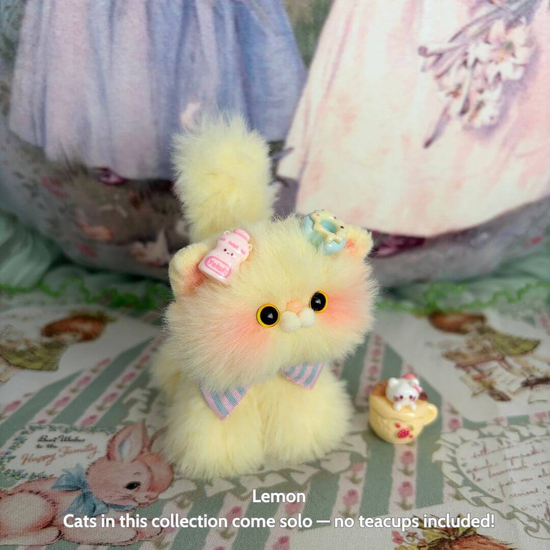 Alt Tag: Fruity Kitten Collection miniature cat in lemon yellow with pastel bows and fluffy fur, posing cutely on patterned fabric.
