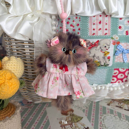 Adorable handmade kitten pendant in a pink floral dress, featuring fluffy fur and cute bows, part of the Pawsh Pendants collection.