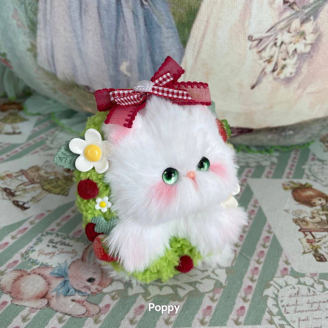 Adorable white handmade kitten figurine with pink cheeks, green accents, floral decorations, and a red bow. Blossom Kitten Collection.