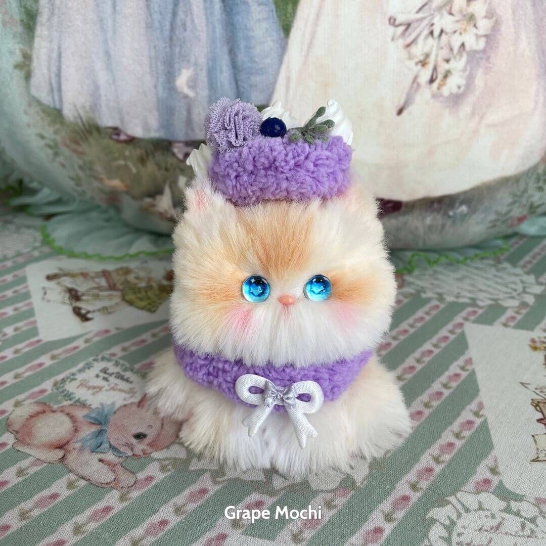 Mewlicious Collection – fluffy kitten with blue eyes, dressed in purple accessories, resembling a cute dessert-themed collectible.