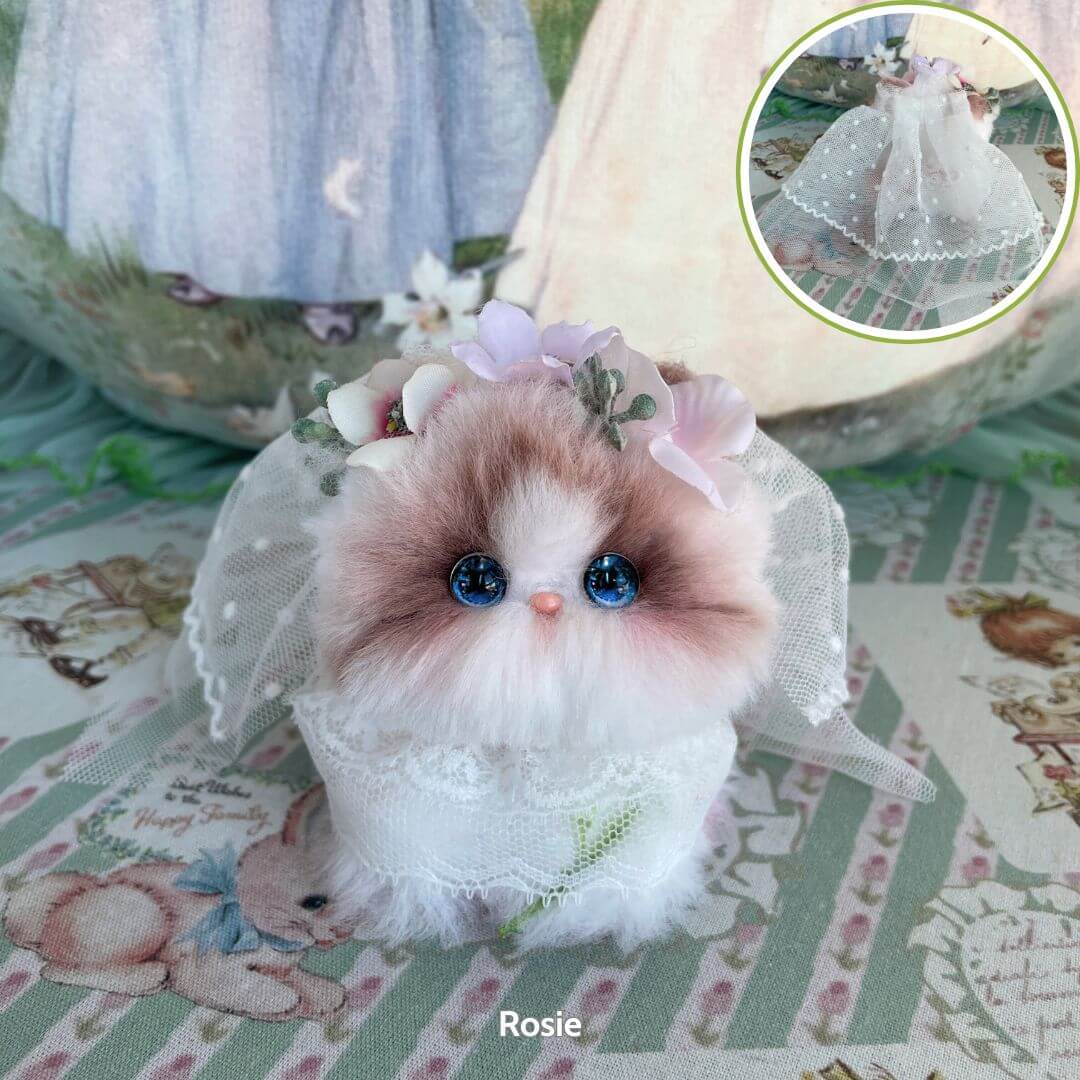 Handmade kitten from Blossom Kitten Collection, fluffy with blue eyes, adorned in a lace veil and floral accents, cute collectible.