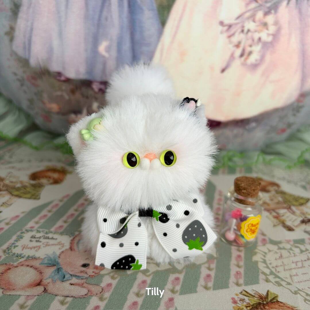 Fluffy Kitten Collection: Tilly, a fluffy white kawaii cat figurine with a bow, strawberry accents, and a cute pose.