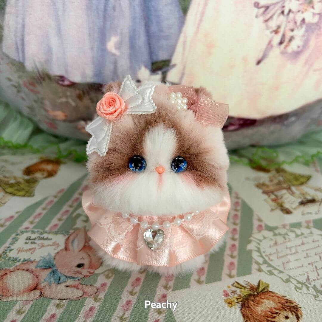 Handmade kitten from the Fairy Paws Collection, featuring fluffy fur, blue eyes, a pink dress, and floral accessories.