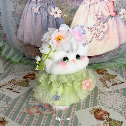 A fluffy kitten figurine from the Enchanted Big Paws Collection, adorned with flowers, wearing a green dress, and featuring expressive eyes.