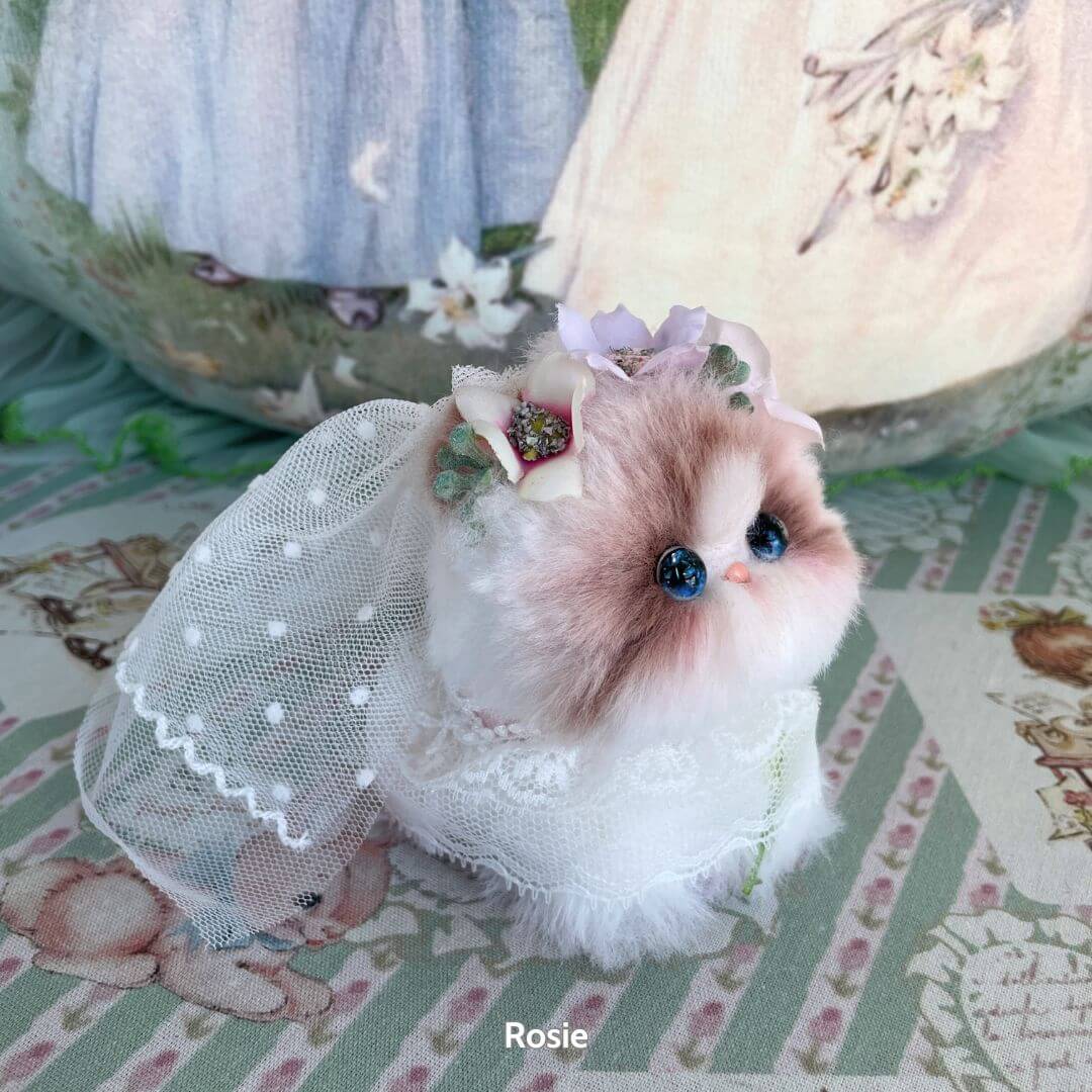 Handmade kitten from the Blossom Kitten Collection dressed in lace with floral accents, featuring cute blue eyes and soft fluffy fur.