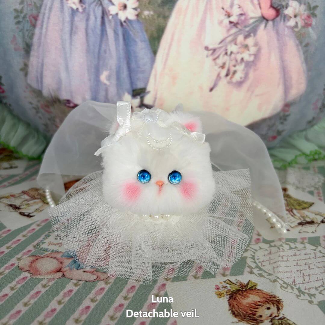 alt_tag: Luna, a fluffy handmade kitten in a wedding veil, featuring hand-painted blue eyes and a lace tulle dress, from the Fairy Paws Collection.