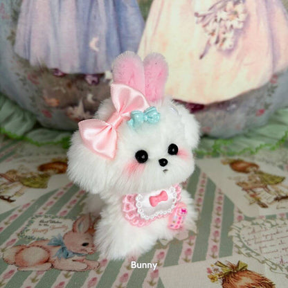 Adorable white puppy from the Cosplay Puppy Collection, featuring pink bunny ears, a large bow, and a cute dress.