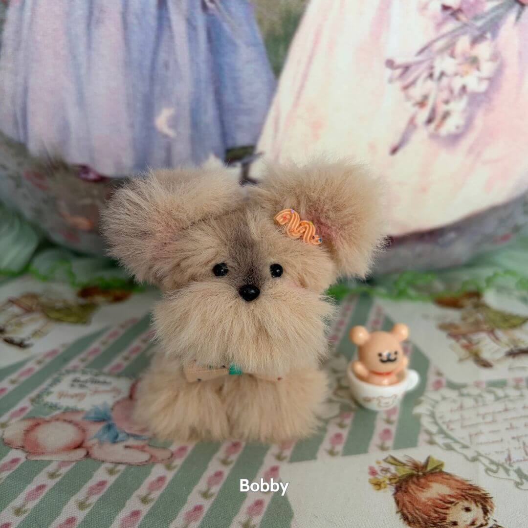 Adorable Puppy Collection handmade fluffy puppy figurine with soft fur, cute black eyes, and orange hair bow, set on a decorative background.