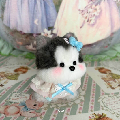 Cute miniature puppy from the Cosplay Puppy Collection, with fluffy gray and white fur, wearing a blue bow and a frilly outfit.
