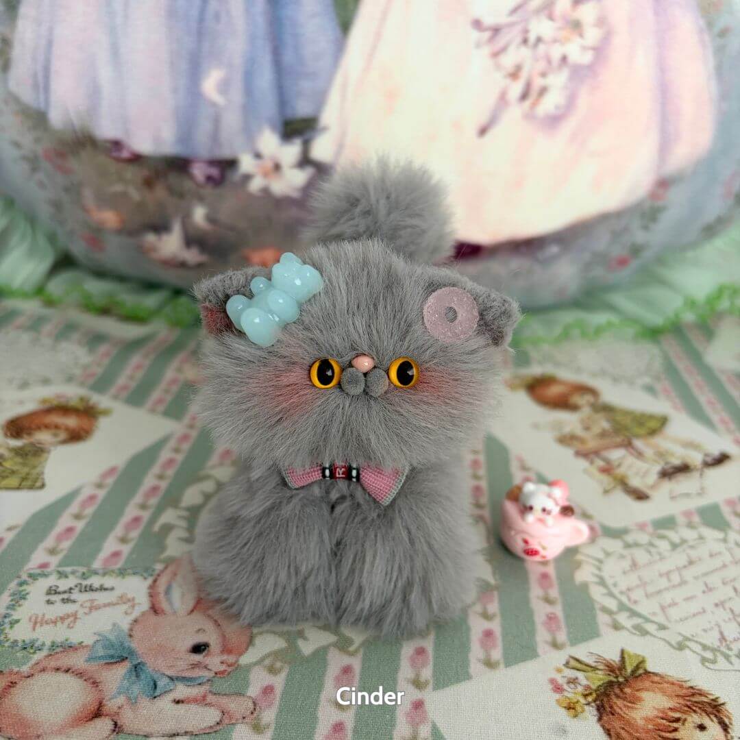 Grey Kitten Collection: handmade kitten in soft grey fur with blue bow, pink bow tie, and cute accessories on pastel patterned background.