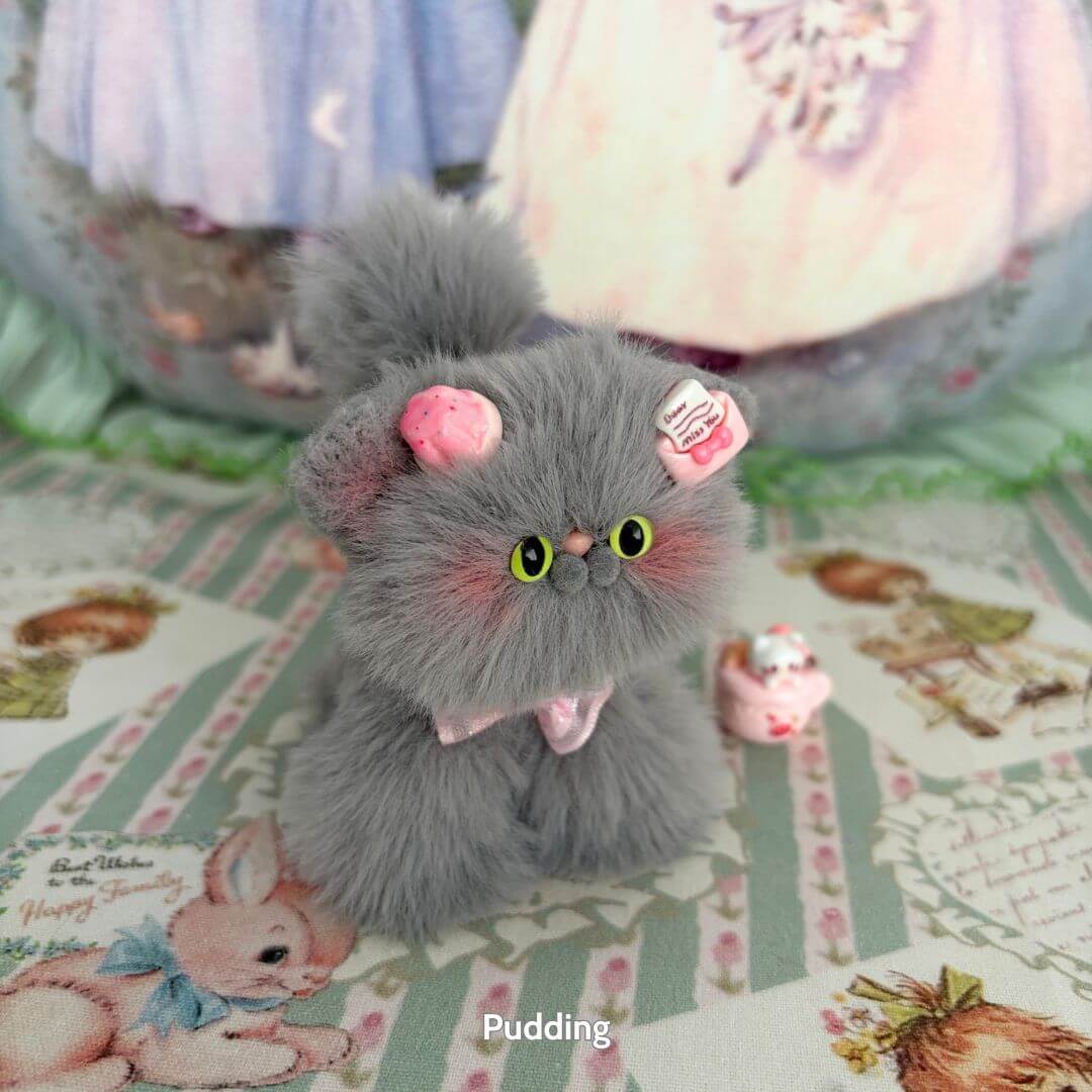Grey Kitten Collection: Fluffy grey kitten figurine with pink cupcake hat, handcrafted in UK, cute collectible cat decoration.
