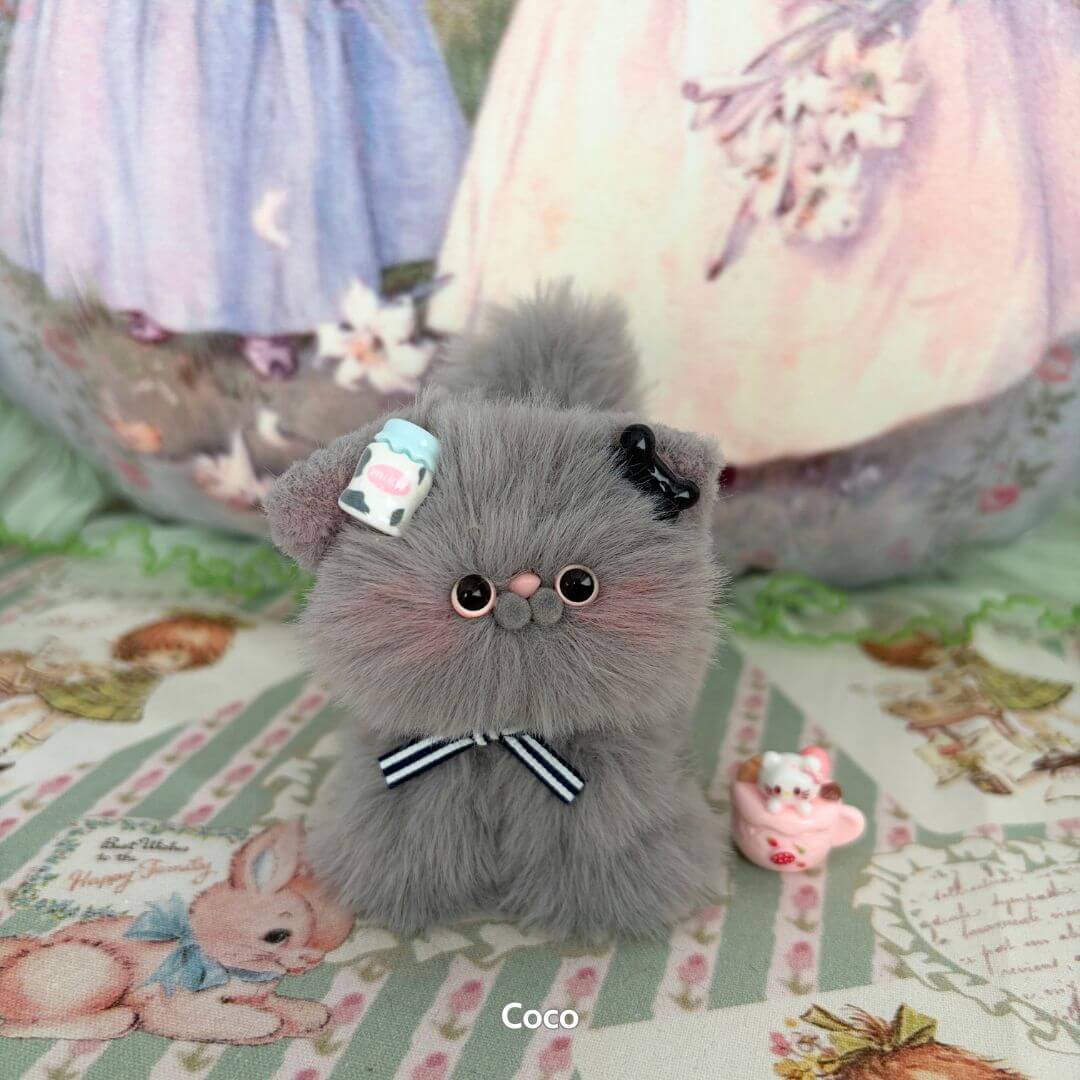 Cute fluffy grey kitten from the Grey Kitten Collection, wearing a blue and black bow, with whimsical accessories.