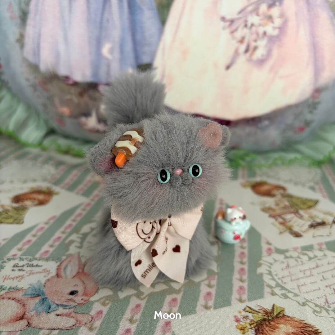 Alt Tag: Adorable handmade kitten from the Grey Kitten Collection with fluffy grey fur, wearing a cute bow and fluffy accessories, posed charmingly.