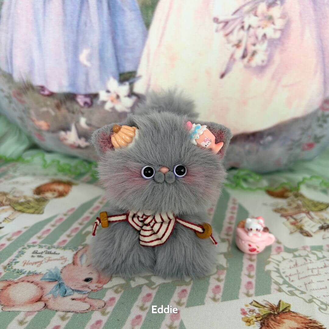 Adorable handmade kitten from the Grey Kitten Collection, featuring fluffy grey fur, cute cupcake accessories, and a whimsical pose.